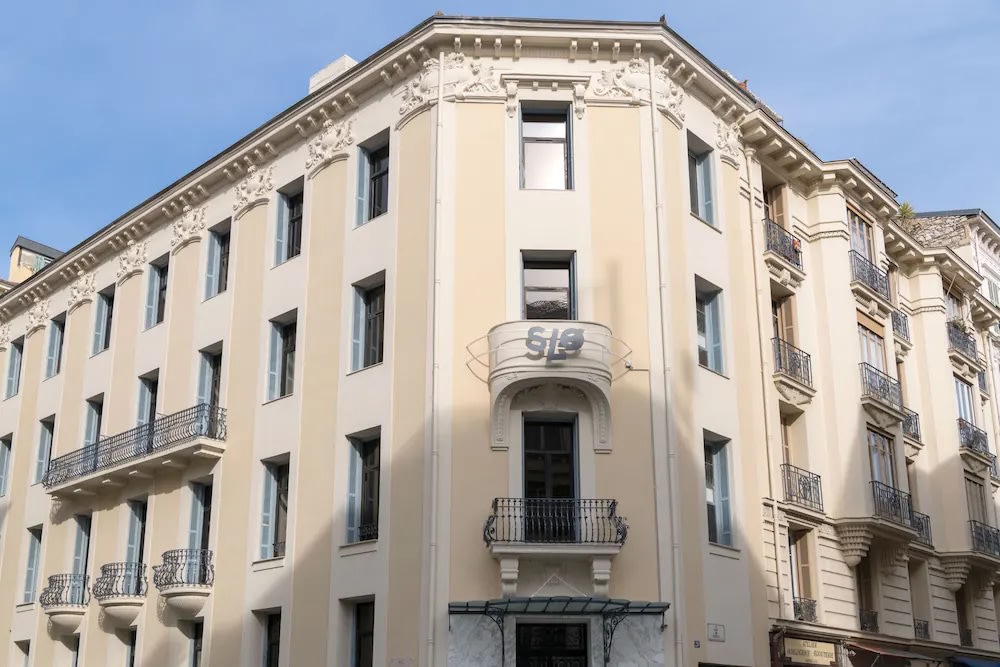 Facade of SLO Nice hostel with balconies and classic Nice architecture