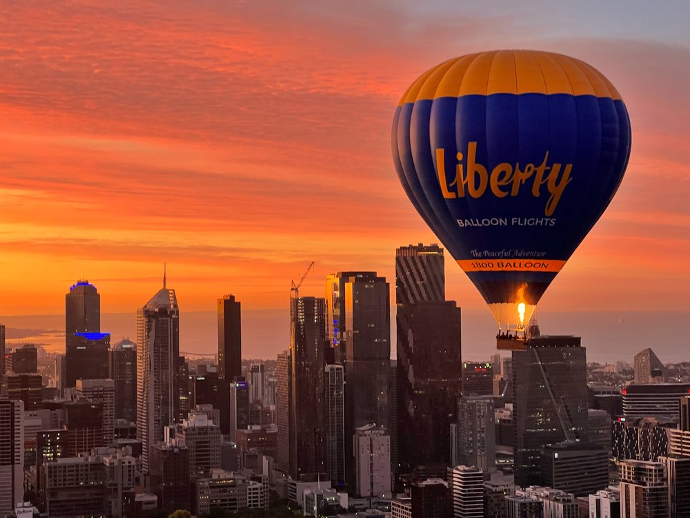 Hot air balloon floating over Melbourne skyline at sunset