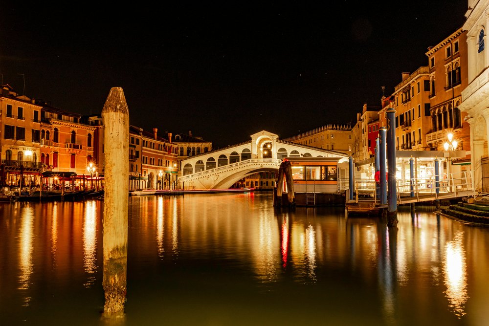 Night view of a Venetian canal and bridge illuminated by lights
