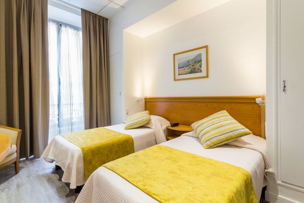  Twin hotel room with yellow bedding and balcony doors