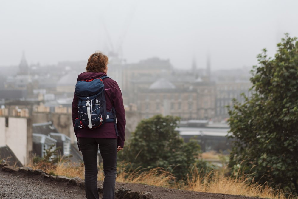 Woman looks out at Edinburgh, engulfed in mist | Photo Credit: Ross Sneddon on Unsplash