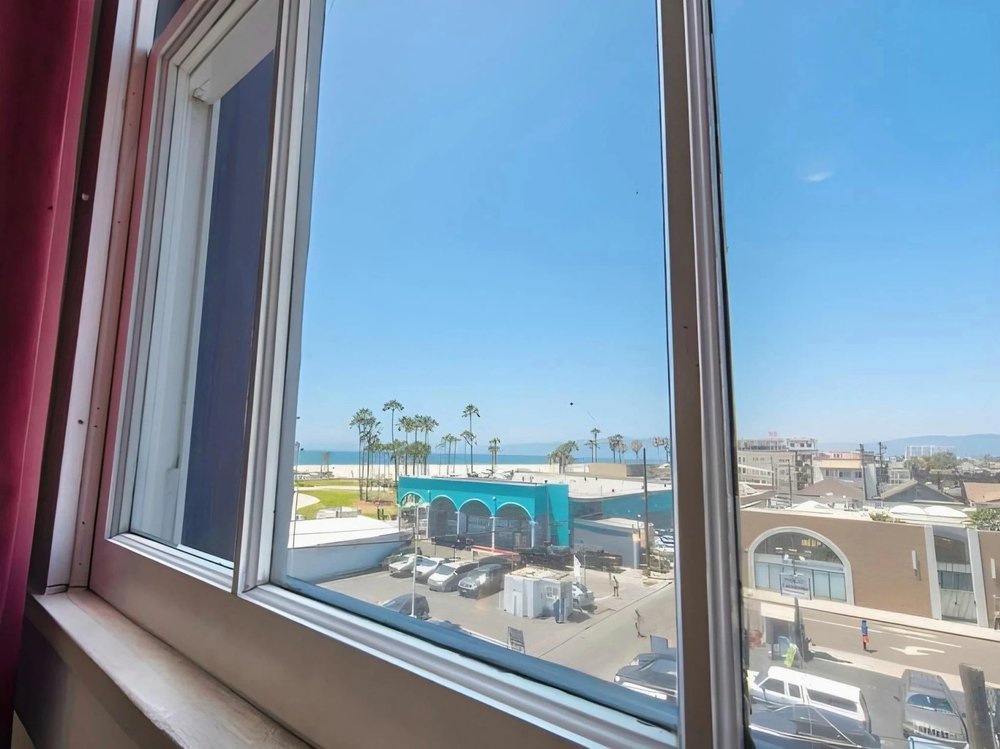 View of Venice Beach and palm trees seen from a hostel window in Los Angeles