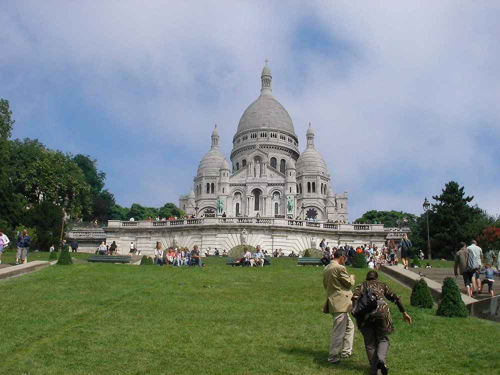 Sacré-Cœur Basilica on Montmartre hill with visitors relaxing outside