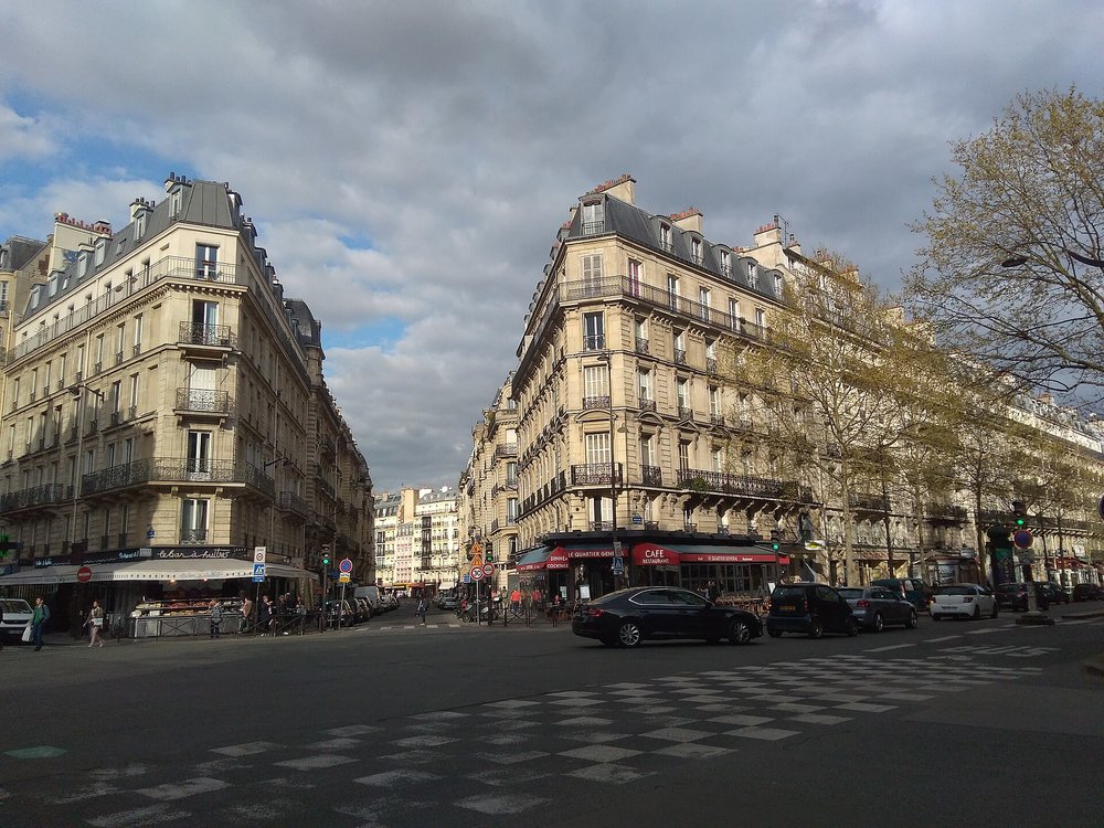Haussmann-style buildings lining a busy Paris street intersection