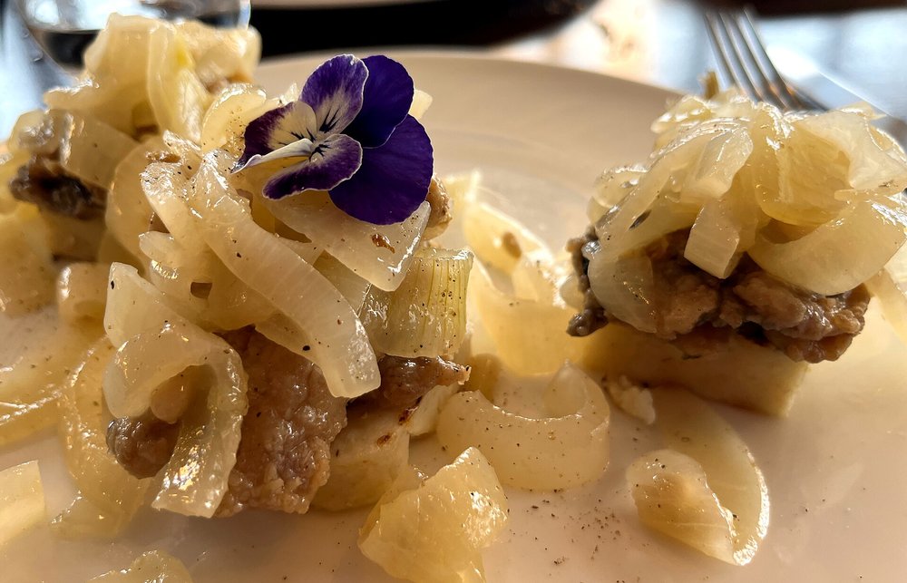 Venetian sarde in saor topped with caramelized onions on a white plate
