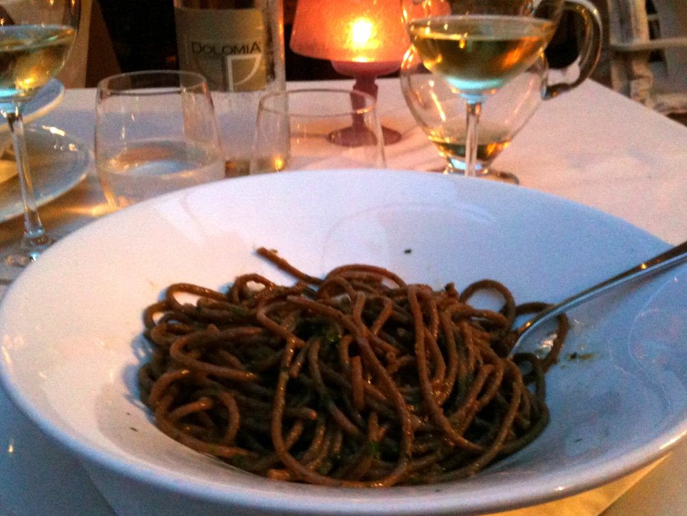 Traditional Venetian bigoli pasta with anchovy and onion sauce on a white plate