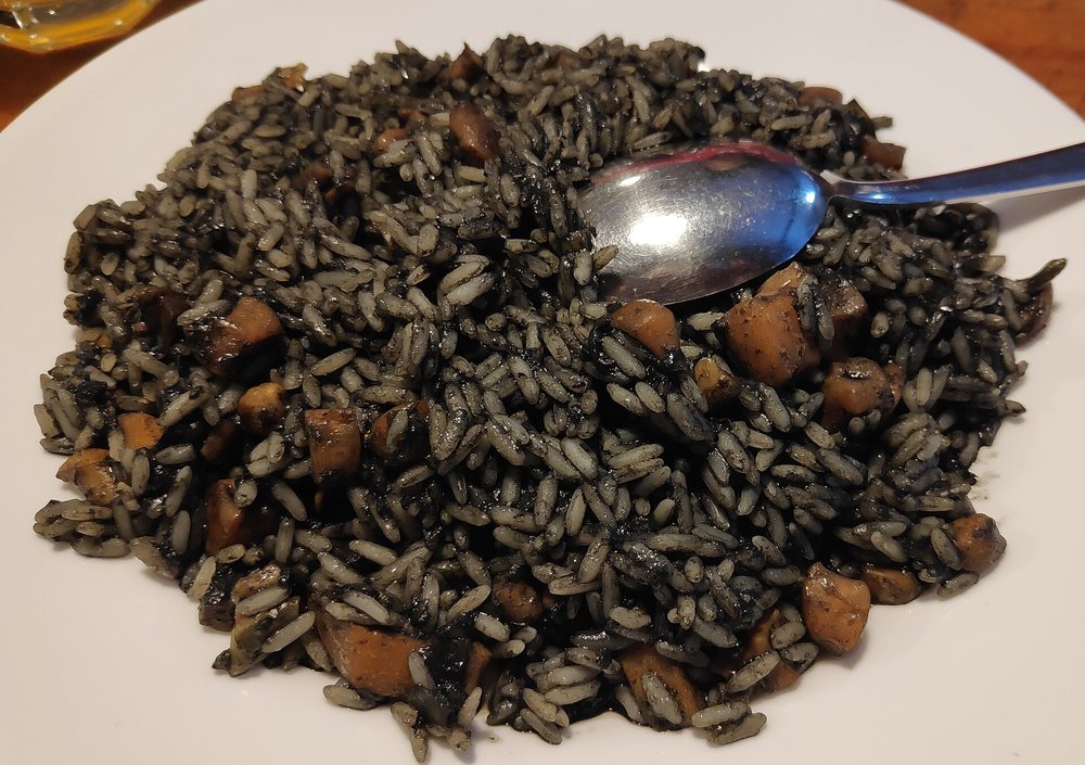 Black risotto with cuttlefish ink and seafood, a traditional Venetian dish