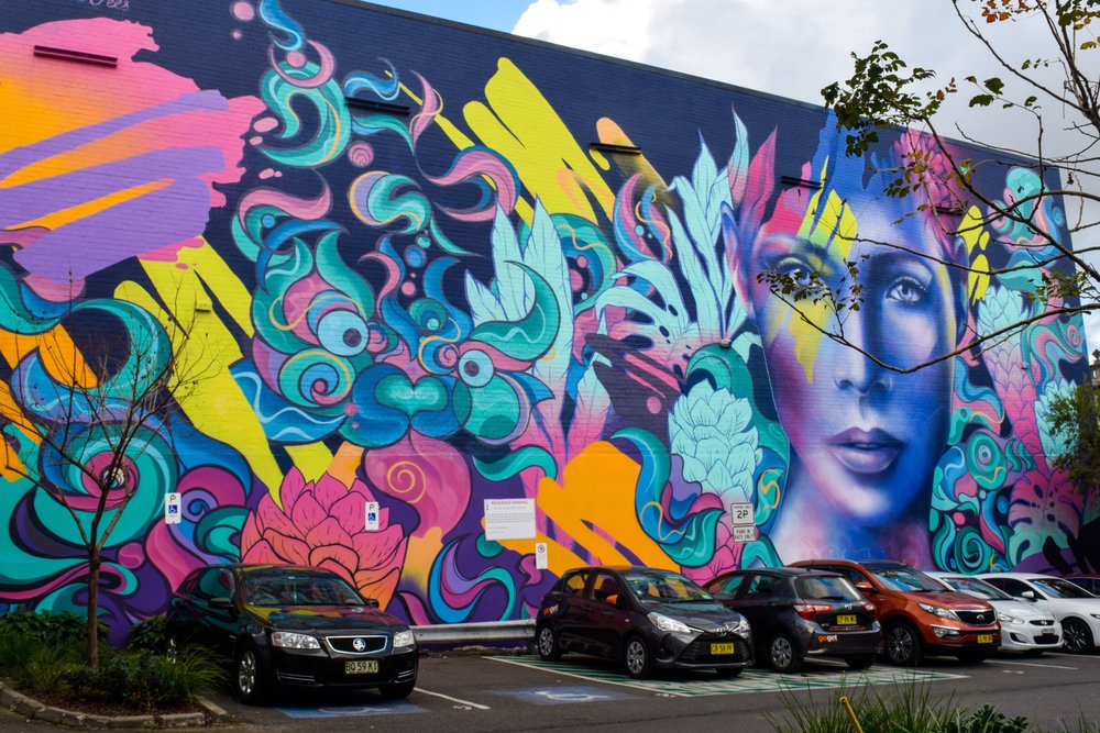 Sydney art galleries - Colorful street art mural in Sydney featuring abstract patterns and a female portrait