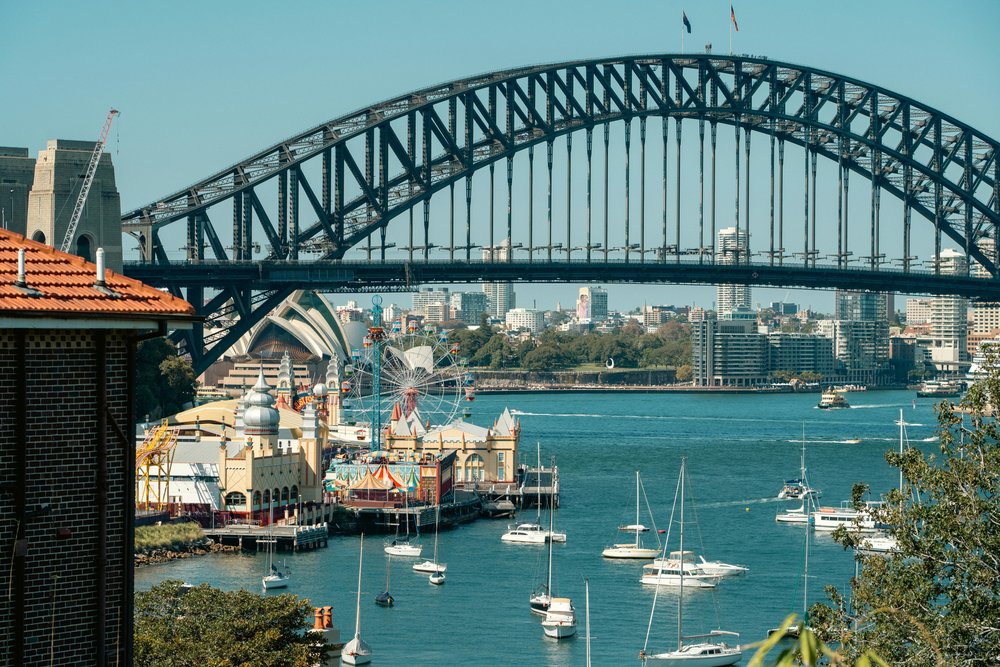 Sydney Harbour Bridge view with boats, Luna Park, and city skyline