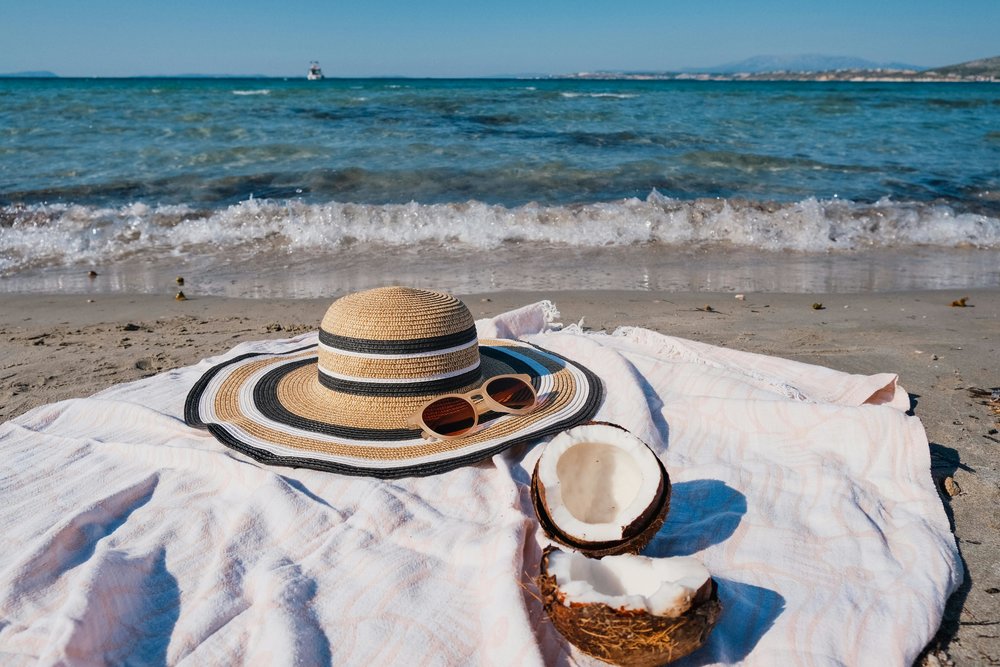 Beach hat, sunglasses and coconut by the beach