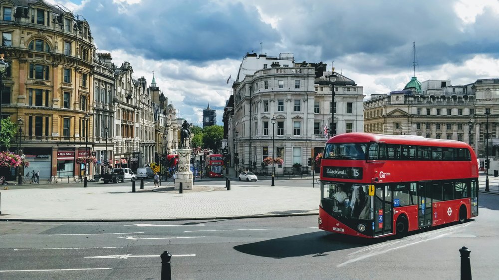 Red double-decker bus driving through a central London street | Photo Credit: Josh Mills on Unsplash