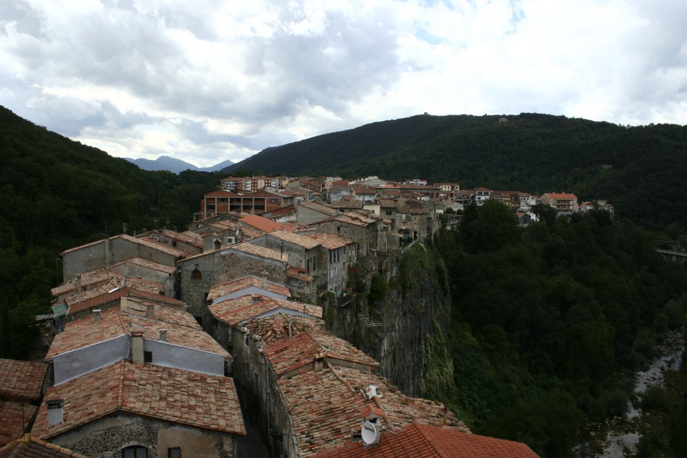 Historic Spanish village built along a rocky cliff surrounded by green hills
