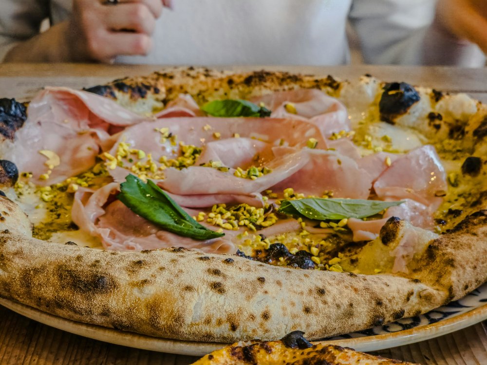 Neapolitan-style pizza with prosciutto, pistachios, and fresh basil