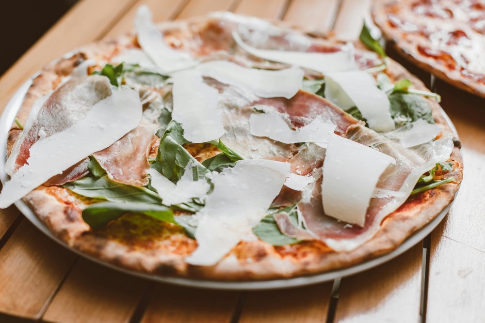 Italian pizza with prosciutto, arugula, and shaved Parmesan cheese