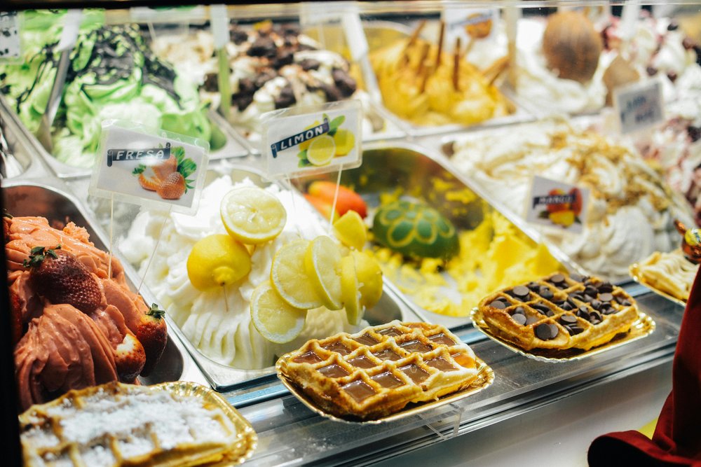 Gelato display in Rome featuring lemon, strawberry, and dessert-inspired flavors