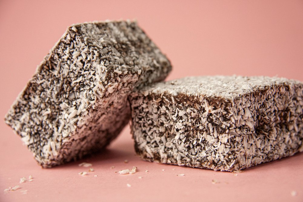 Lamington dessert coated in chocolate and coconut flakes
