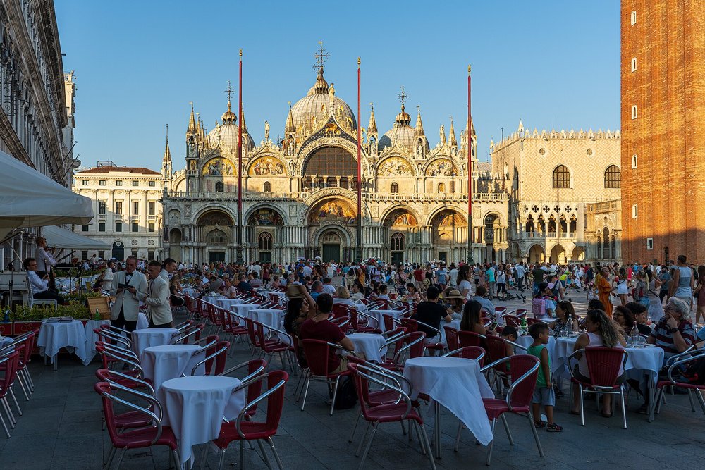 Crowds dining outdoors at St. Mark’s Square on a sunny day in Venice