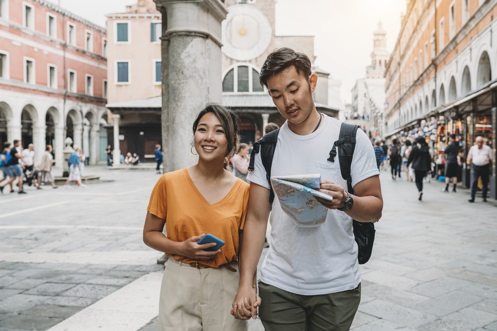 Couple holding hands and checking a map while sightseeing in Venice