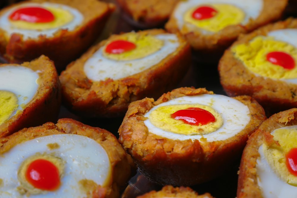 Scotch eggs cut open showing egg and seasoned meat coating
