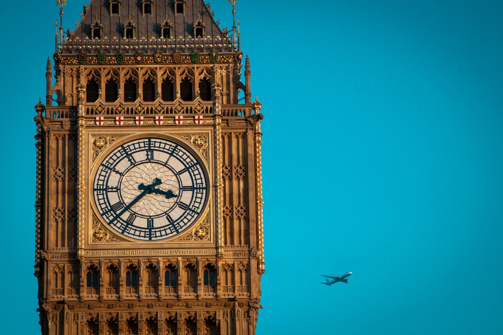Big Ben tower with blue sky and airplane flying past