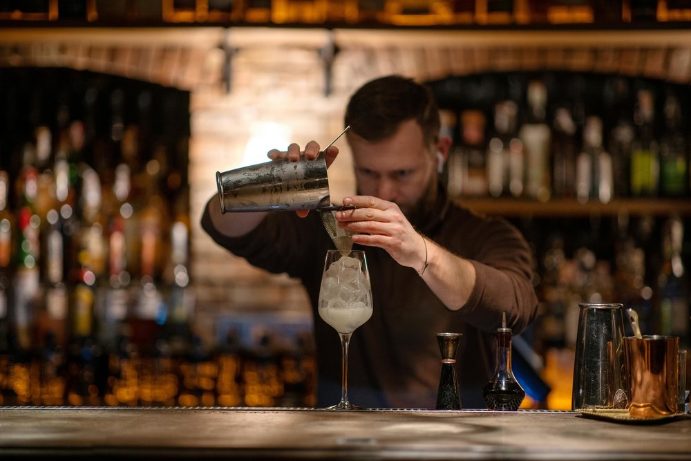 Bartender making a cocktail behind the bar in Auckland nightlife setting