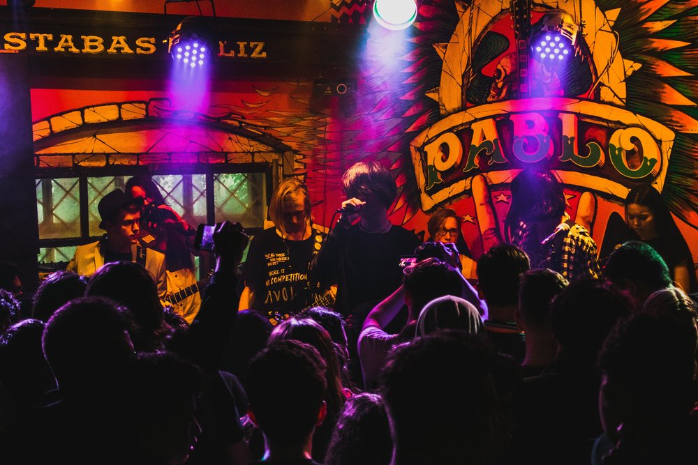 Crowd watching a live band perform inside a lively Auckland bar