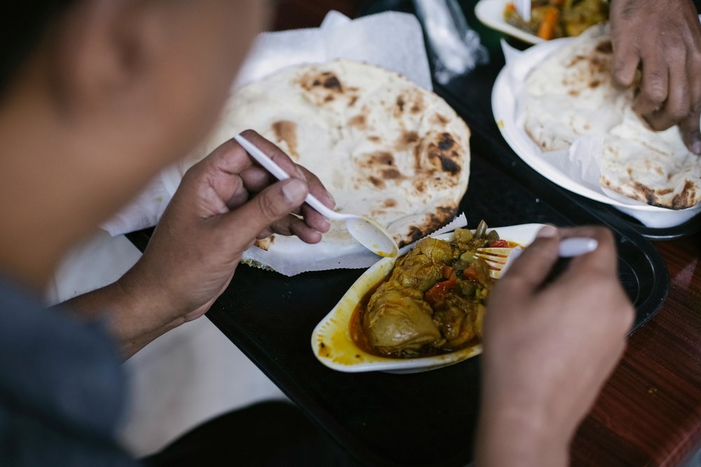 People eating cheap curry and flatbread at a budget restaurant in Sydney