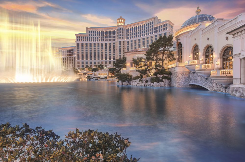 Bellagio Hotel and Casino with fountain show at dusk, reflecting on the lake with elegant architecture