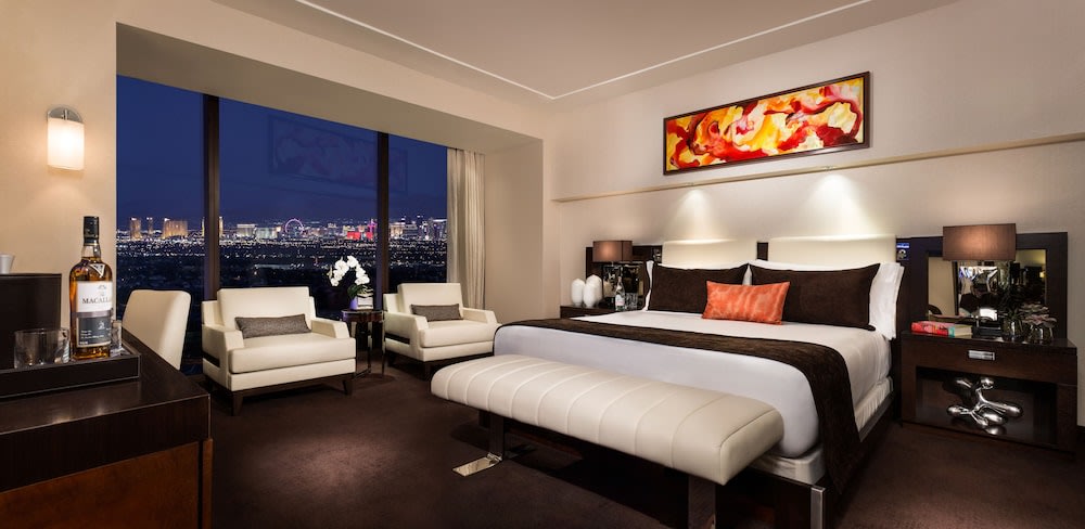 Upscale Red Rock Resort hotel room with king bed, seating area, and floor-to-ceiling window overlooking Las Vegas