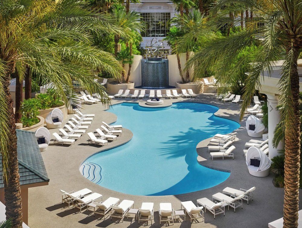Luxury Four Seasons Las Vegas pool with palm-lined deck, lounge chairs, cabanas, and peaceful resort setting