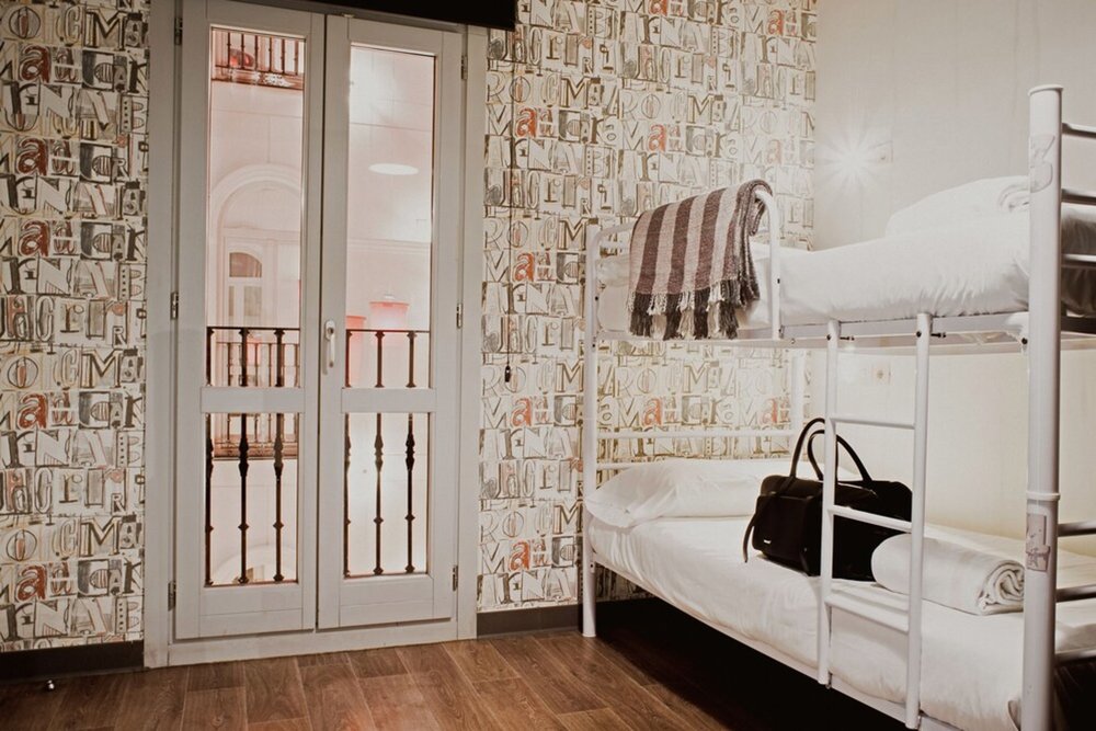 Youth hostel dorm room with bunk beds and balcony doors in Madrid