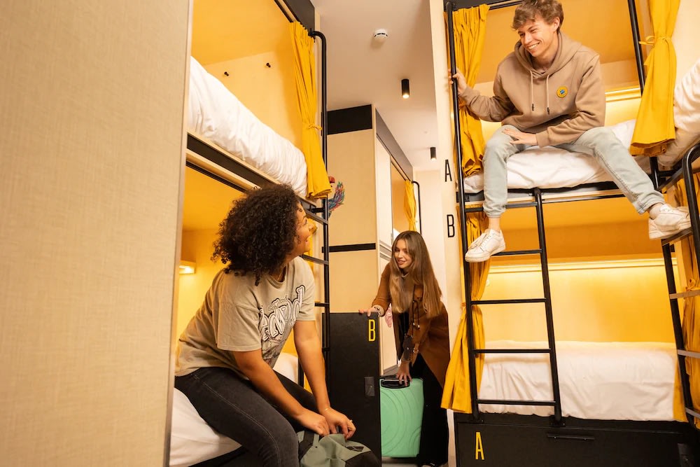 Group of travelers chatting inside a modern youth hostel dorm in Madrid