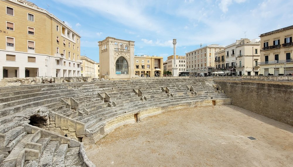 Ancient Roman amphitheater surrounded by buildings in Lecce, Italy