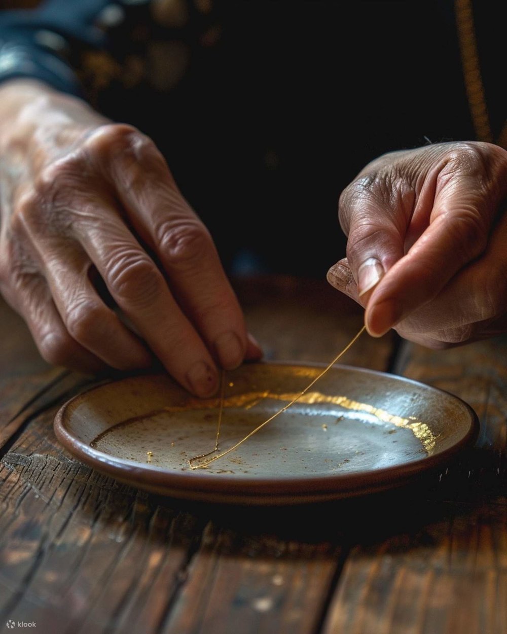A person repairs a ceramic plate with gold