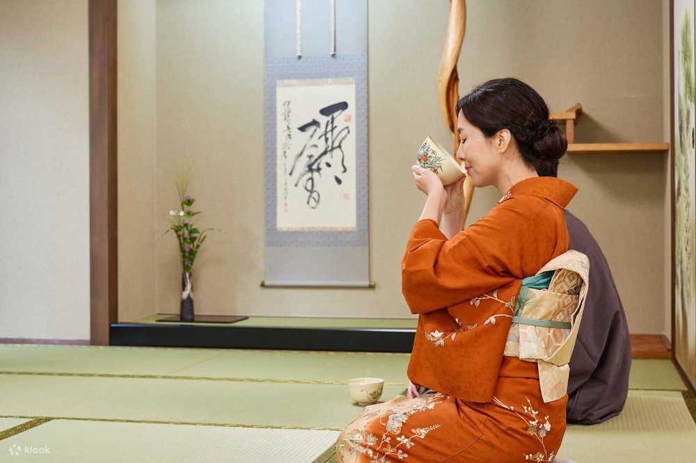 A woman wearing a kimono drinks tea