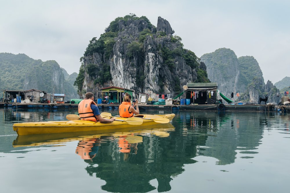 Tourists kayaking in Halong Bay, Vietnam, surrounded by dramatic cliffs