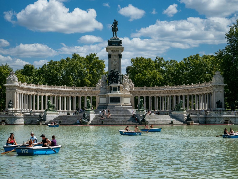 Rowboats on the lake at El Retiro Park, Madrid, with clear skies and trees | Photo Credit: Karabo Photo on Pexels