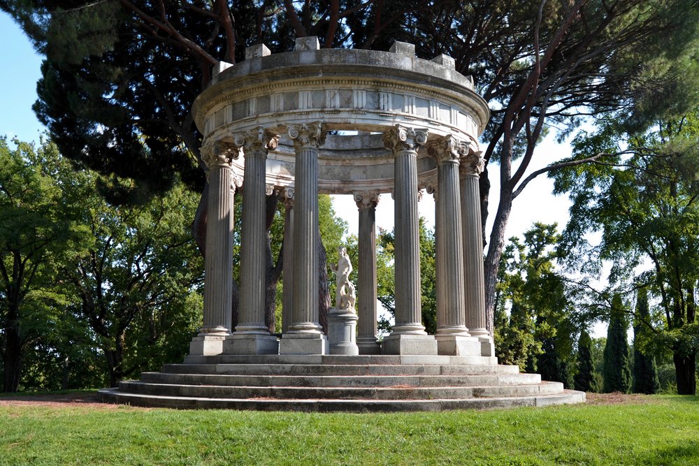 Classical temple structure surrounded by greenery in El Capricho Park, Madrid | Photo Credit: Wikimedia Commons