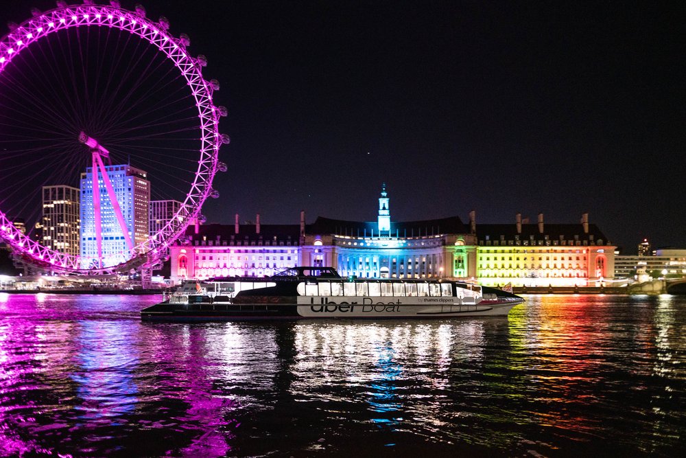 Thames river cruise boat with London Eye lit up at night