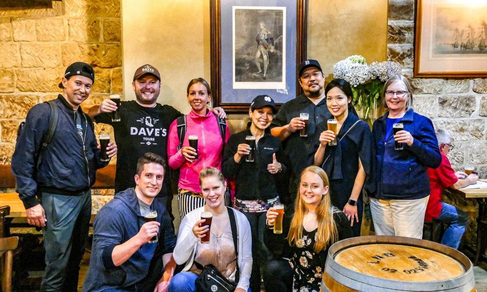 Group holding beers inside historic Australian pub during guided tour