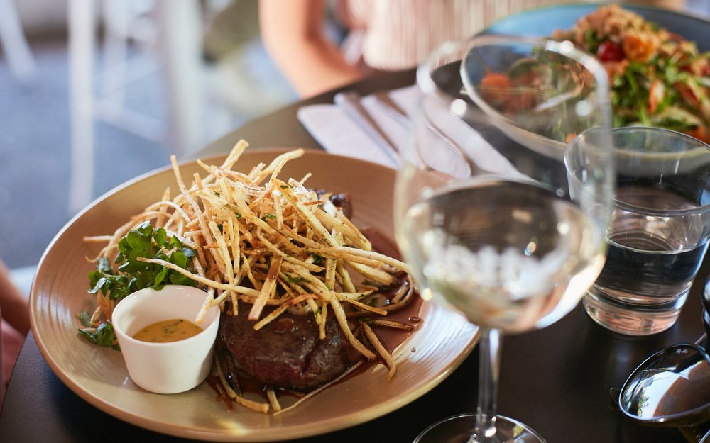 Grilled steak with shoestring fries and white wine at Australian restaurant