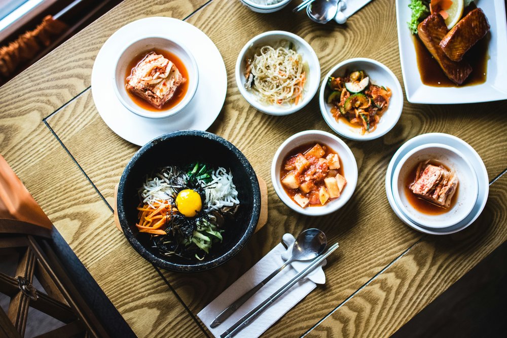 A bowl of bibimbap with colorful vegetables and a fried egg | Photo Credit: Jakub Kapusnak on Unsplash
