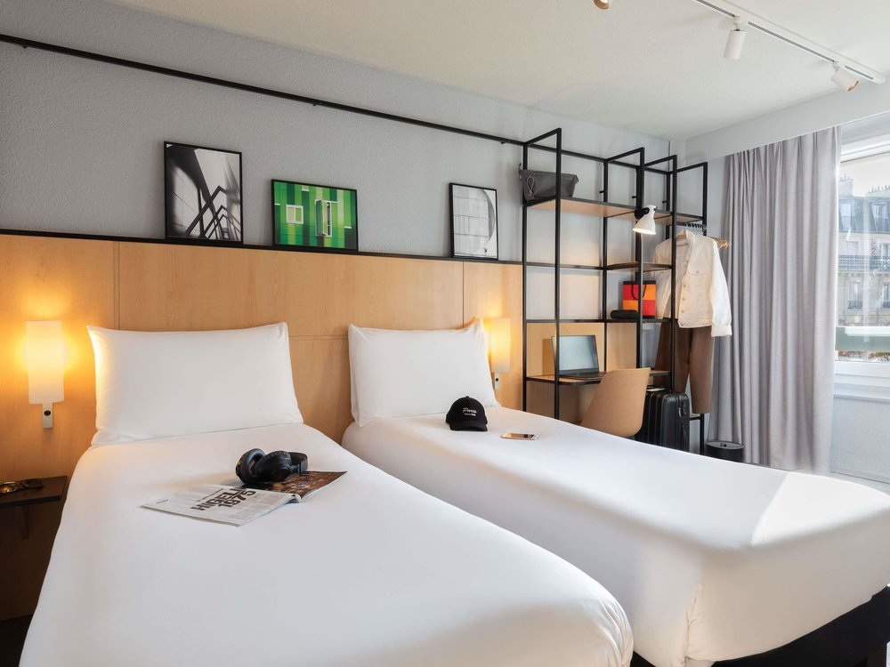 Clean twin beds in Ibis Paris hotel room with minimalist decor