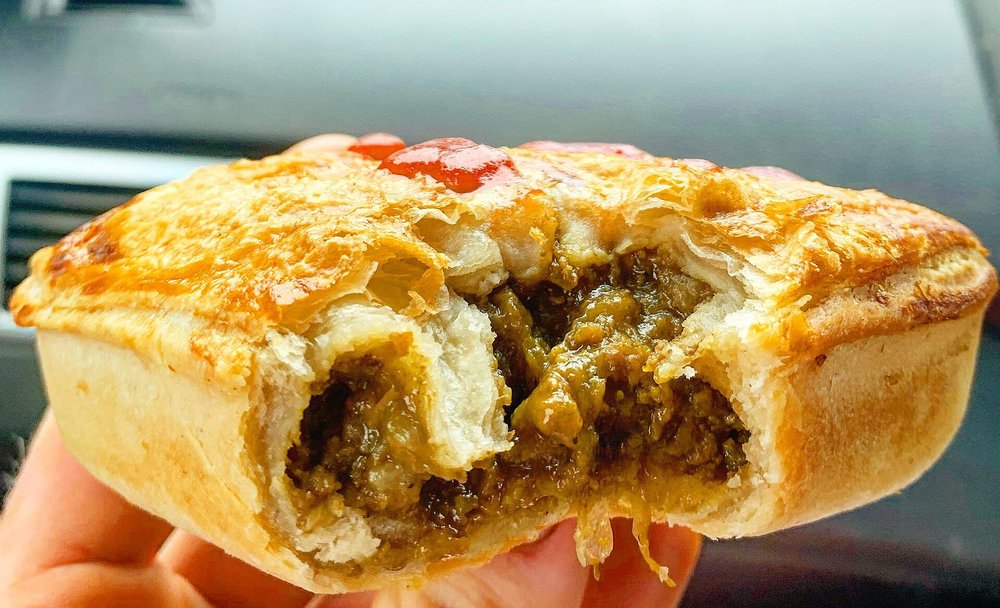 Close-up of Australian meat pie with beef gravy inside flaky pastry