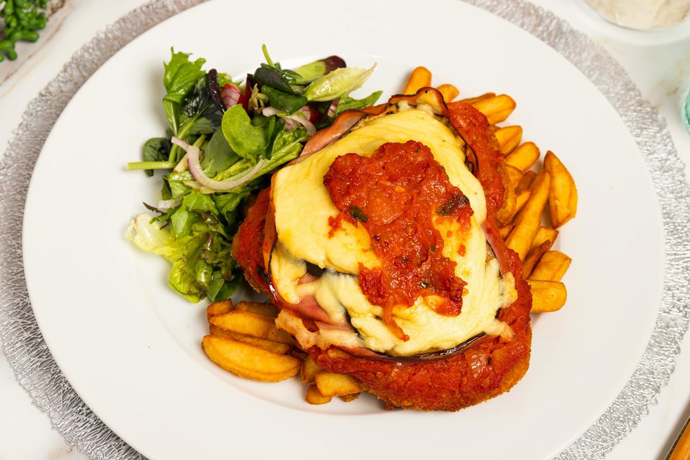 Chicken parmigiana topped with cheese and tomato sauce served with fries