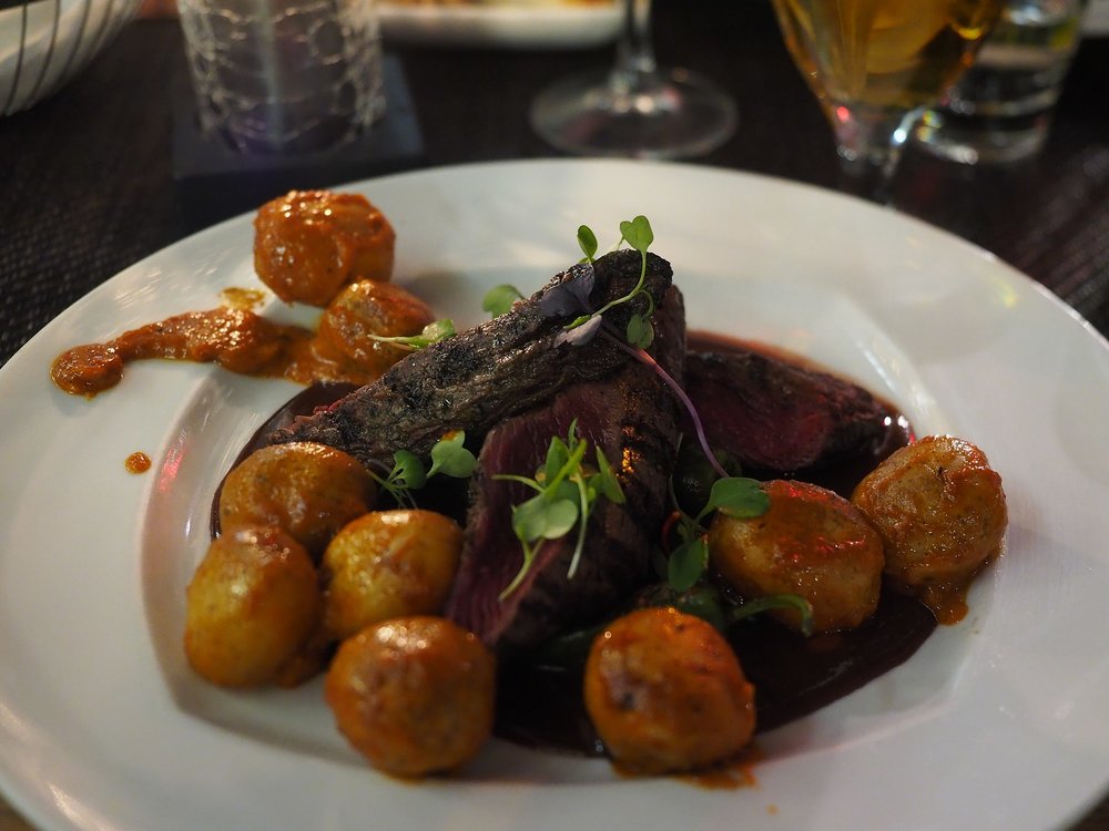 Medium-rare kangaroo steak with baby potatoes on a white plate