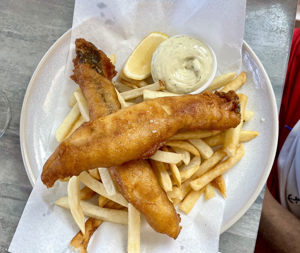 Golden battered fish fillets served with fries and dipping sauce