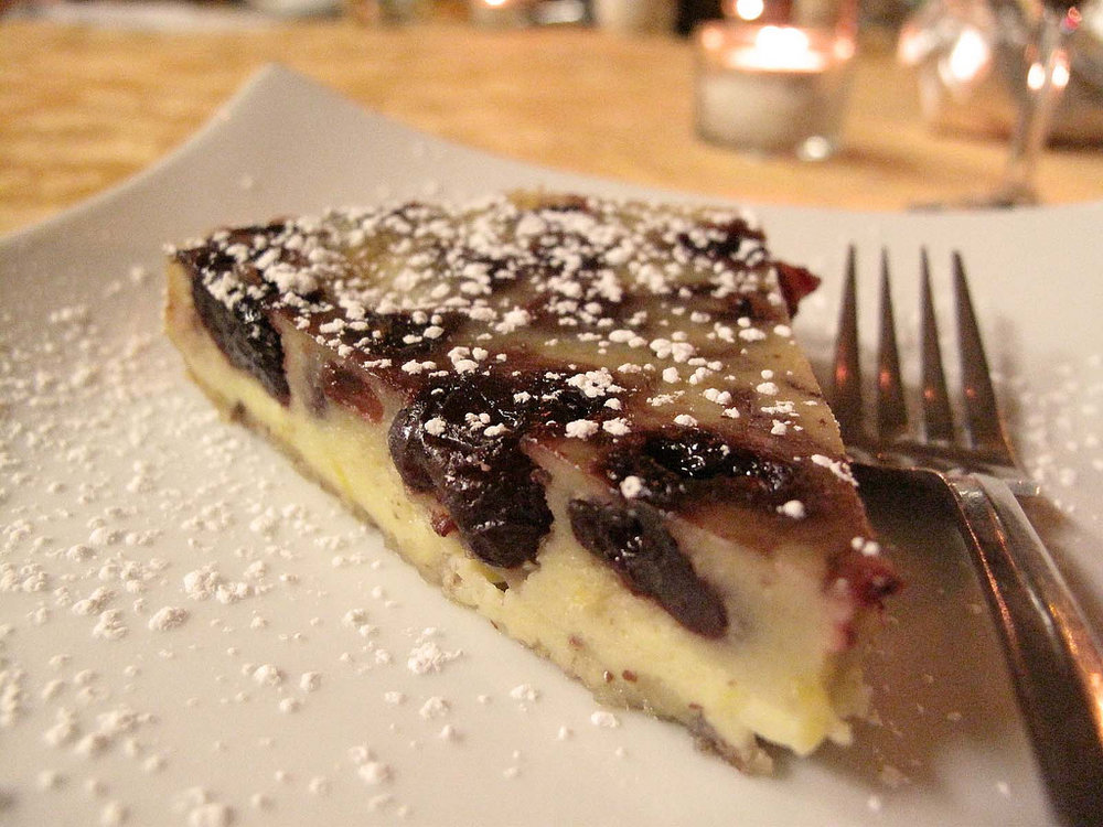 Cherry clafoutis slice with baked custard and powdered sugar topping