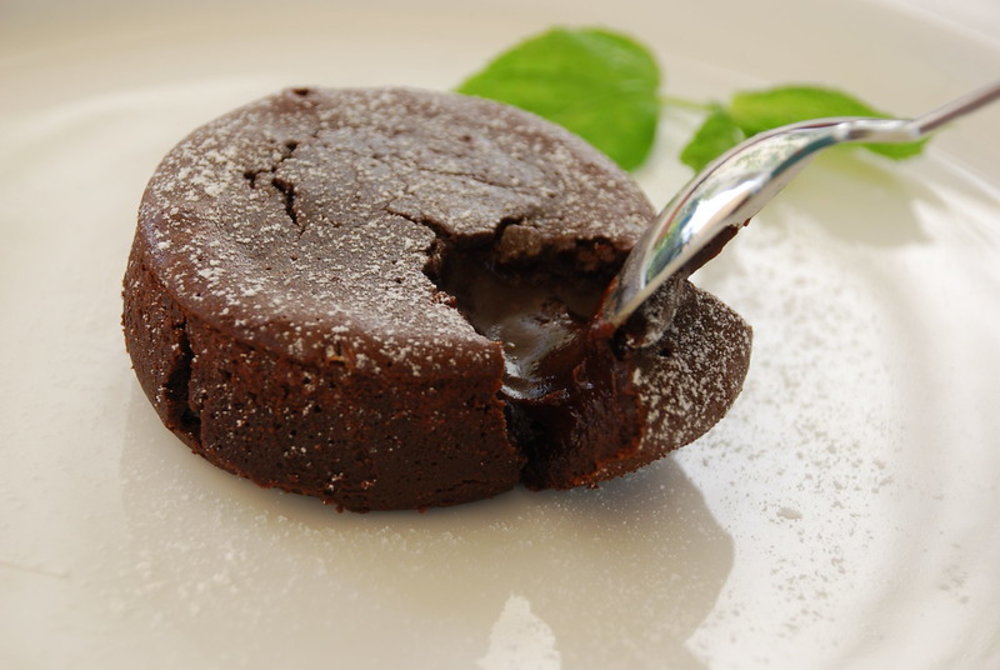 Chocolate soufflé with gooey center being scooped with spoon