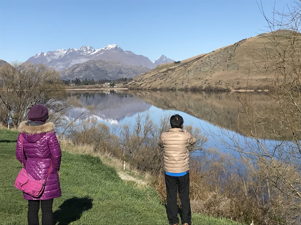 Visitors admiring autumn scenery and mountain reflections near Arrowtown, New Zealand